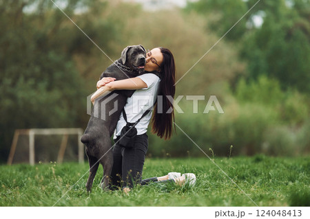 Hugs the pet. Young brunette is having a walk with her dog outdoors Hugs the pet. Young brunette is having a walk with her dog outdoors 124048413