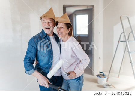 Portrait of senior couple having fun while painting walls with roller in new home. 124049026