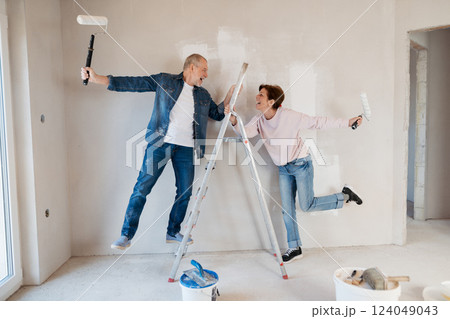 Senior husband and wife standing on a ladder repainting the walls. Senior husband and wife standing on a ladder repainting the walls. 124049043