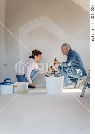 Senior husband and wife repainting the walls. 124049083