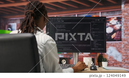 Programmer types code into PC, entering commands, running script. African american IT professional in apartment fixing errors in application, implementing new features, camera B Programmer types code into PC, entering commands, running script. African american IT professional in apartment fixing errors in application, implementing new features, camera B 124049149