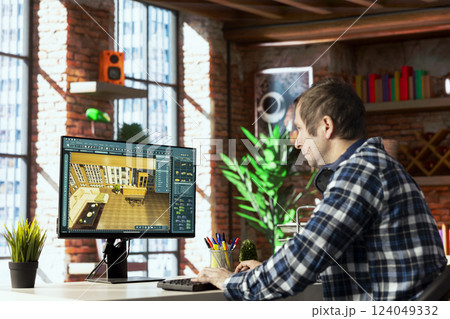 Interior designer sitting at desk using 3D modeling software on computer, moving furniture assets. Architectural designer aligns items into position, saves configuration for client approval 124049332