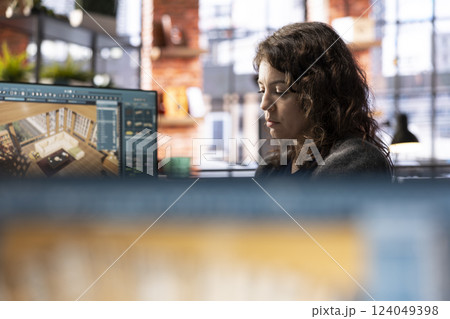 Young woman editor uses digital interface to design an apartment floor plan, working on a 3D modeling project. Architectural software enables professional rendering and virtual home configuration. 124049398