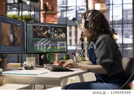 Female filmmaker working on media post production from agency office, ensuring the editing timeline and color correction for a video shoot. Tech driven workspace showcases a digital workflow. 124049399