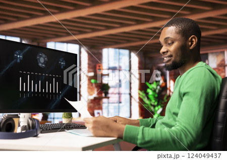 Upbeat teleworker using financial software user interface on PC screen in apartment showing company growth graphs. Man looking at sales statistics on computer display showing income figures Upbeat teleworker using financial software user interface on PC screen in apartment showing company growth graphs. Man looking at sales statistics on computer display showing income figures 124049437