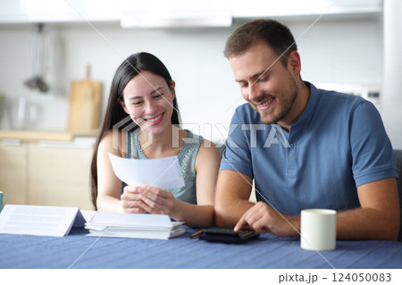 Happy interracial couple calculating expenses uisng calculator Happy interracial couple calculating expenses uisng calculator 124050083