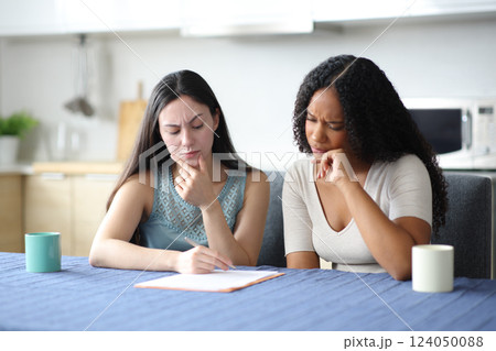 Suspicious interracial roommates reading a contrat in the kitchen 124050088
