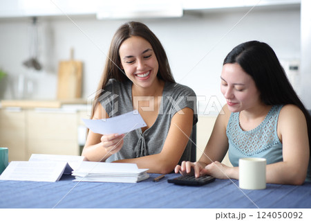 Happy interracial couple calculting expenses checking bill 124050092