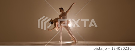 Banner. Young ballerina in tutu, leaning on elegant man with extended arm, under soft illumination highlights their silhouettes. 124050230