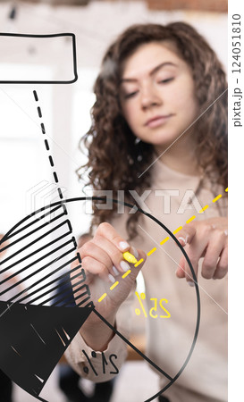 Businesswoman calculating market insights, drawing segmented pie chart with yellow marker, analyzing financial statistics 124051810