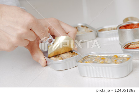 man opening some cans of canned food 124051868