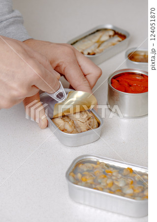 man opening a can of frigate tuna fillets 124051870