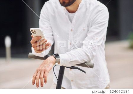 Close up view. Stylish man is with his scooter outdoors at daytime 124052154