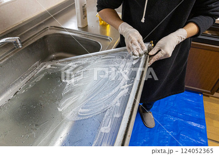 ガラス窓を外して洗剤で洗っている人物の手元 124052365