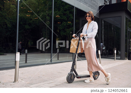 In sunglasses. Beautiful young woman is with her scooter outdoors 124052661