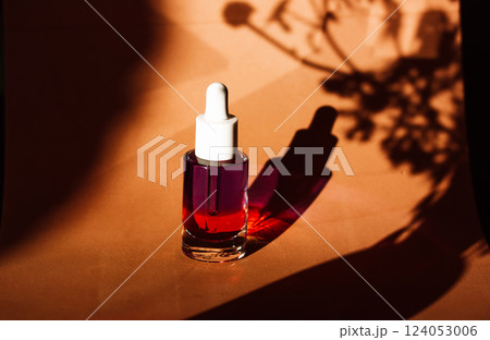 Glass cosmetic bottle with serum for face skin care on yellow background. Female beauty product. Face serums on natural backdrop with plants shadows. Glass cosmetic bottle with serum for face skin care on yellow background. Female beauty product. Face serums on natural backdrop with plants shadows. 124053006