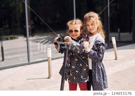 Two girls having fun on the scooter outdoors at daytime 124053176