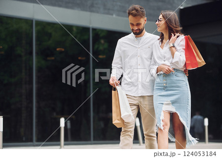 Walking near modern building. Beautiful couple have a shopping day outdoors at daytime 124053184