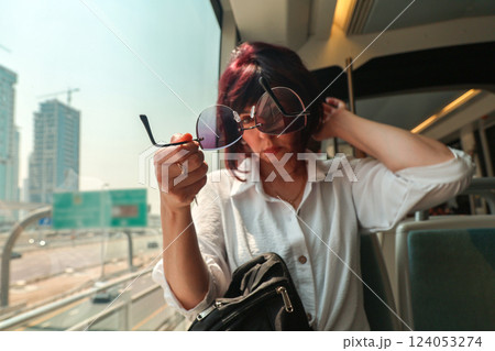 A woman in a subway car combs her hair because she overslept and is late for work A woman in a subway car combs her hair because she overslept and is late for work 124053274