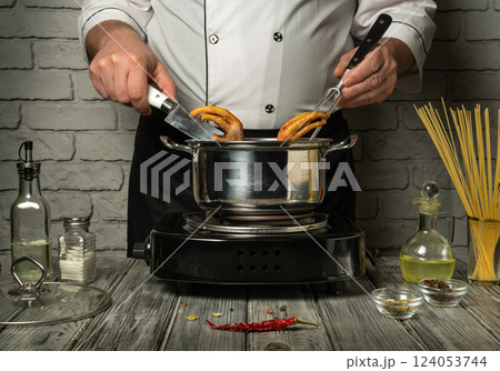 In a modern kitchen with rustic touches, a chef skillfully prepares chicken feet while cooking pasta in a pot on the stove, demonstrating culinary skill and concentration In a modern kitchen with rustic touches, a chef skillfully prepares chicken feet while cooking pasta in a pot on the stove, demonstrating culinary skill and concentration 124053744