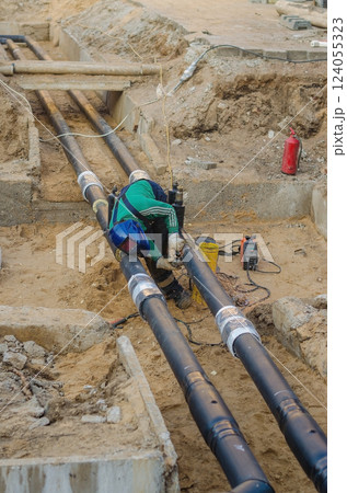 Welder working on underground pipeline installation at a construction site. High quality photo Welder working on underground pipeline installation at a construction site. High quality photo 124055323