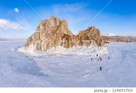 Aerial top view to famous Shamanka rock and small sea covered with snow. Winter landscape. Popular touristic destination, Clear ice. Cape Burkhan on Olkhon island, frozen Baikal lake, Siberia, Russia. 124055703