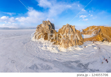 Aerial top view to famous Shamanka rock and small sea covered with snow. Winter landscape. Popular touristic destination, Clear ice. Cape Burkhan on Olkhon island, frozen Baikal lake, Siberia, Russia. 124055706