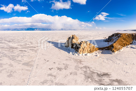 Aerial top view to famous Shamanka rock and small sea covered with snow. Winter landscape. Popular touristic destination, Clear ice. Cape Burkhan on Olkhon island, frozen Baikal lake, Siberia, Russia. Aerial top view to famous Shamanka rock and small sea covered with snow. Winter landscape. Popular touristic destination, Clear ice. Cape Burkhan on Olkhon island, frozen Baikal lake, Siberia, Russia. 124055707
