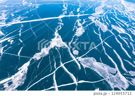 Aerial top view to Blue clear ice lake Baikal. Crack covered snow on frozen water surface. Cold winter landscape with mountains, sunny day, Natural background. , Russia, Siberia. 124055712