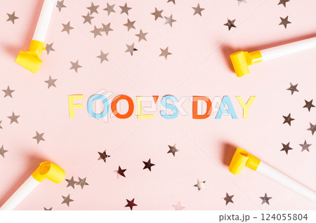 April Fools' Day written in colored letters, whistles, stars and tulips on pink top view 124055804