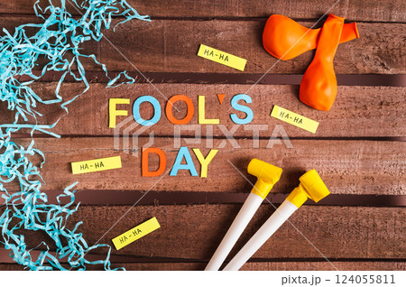 April Fools' Day from colored letters, funny notes, whistles and balloons on a wooden background April Fools' Day from colored letters, funny notes, whistles and balloons on a wooden background 124055811
