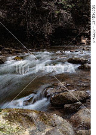 This image captures a fast-flowing river rushing over a rocky bed, creating whitewater rapids. This image captures a fast-flowing river rushing over a rocky bed, creating whitewater rapids. 124056559