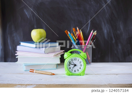 Back to school, stationery, alarm clock, stack of books, on wooden table with chalkboard background. Back to school, stationery, alarm clock, stack of books, on wooden table with chalkboard background. 124057184