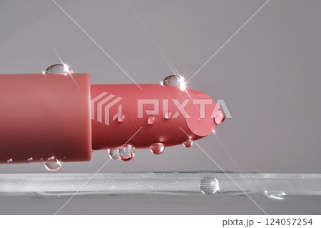 Classic lipstick with drops of water on a neutral background. 124057254