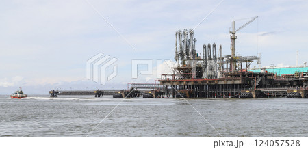 Offshore oil jetty operating in open water, featuring cranes and pipelines 124057528