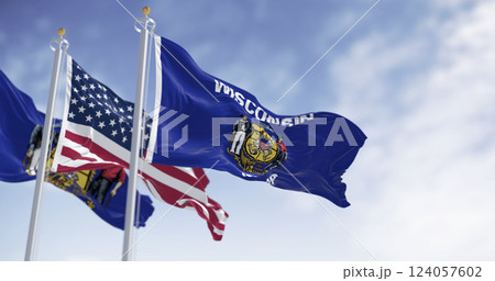 Wisconsin and USA flags waving on flagpoles outdoors against blue sky Wisconsin and USA flags waving on flagpoles outdoors against blue sky 124057602
