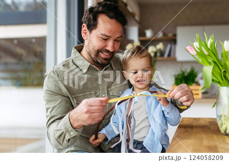 Father and little boy braiding easter whip from willow branches. Easter tradition concept. 124058209