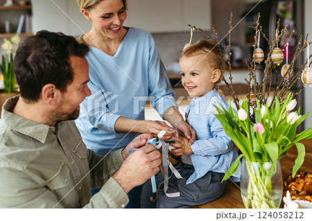 Parents helping little boy to decorate easter whip from willow branches with ribbons. Easter tradition concept. Parents helping little boy to decorate easter whip from willow branches with ribbons. Easter tradition concept. 124058212