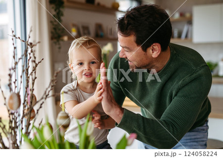 Father and little son decorating pussy willows branches, putting easter eggs on them. Father and little son decorating pussy willows branches, putting easter eggs on them. 124058224