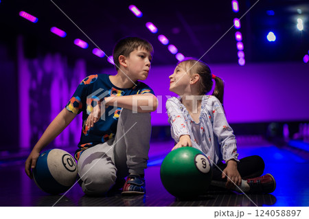 Two Young choldren girl boy siblings having fun and playing bowling Two Young choldren girl boy siblings having fun and playing bowling 124058897