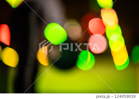 Hand reaching for vibrant bowling ball in colorful, well-lit bowling alley with various balls and blurred background creating dynamic atmosphere 124059039