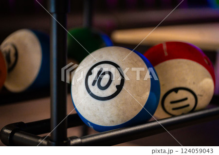 Hand reaching for vibrant bowling ball in colorful, well-lit bowling alley with various balls and blurred background creating dynamic atmosphere Hand reaching for vibrant bowling ball in colorful, well-lit bowling alley with various balls and blurred background creating dynamic atmosphere 124059043