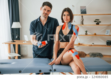 Beautiful portrait. Finished result. Woman visiting physiologist that putting kinesio tape on the skin 124060085