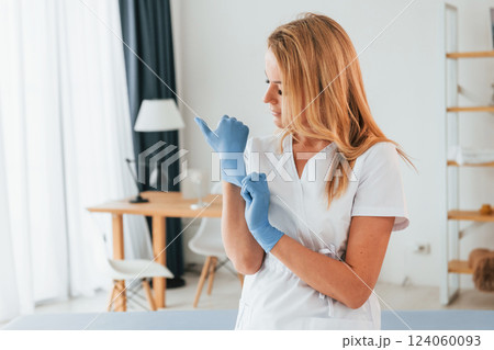 Wearing gloves. Female doctor in white coat is standing in the clinic 124060093