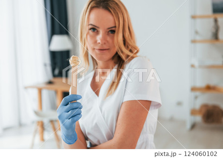 With sugaring gel stick. Female doctor in white coat is standing in the clinic With sugaring gel stick. Female doctor in white coat is standing in the clinic 124060102