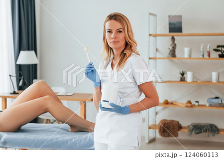 Holding stick with gel. Woman is having sugaring procedure in the clinic by female doctor Holding stick with gel. Woman is having sugaring procedure in the clinic by female doctor 124060113