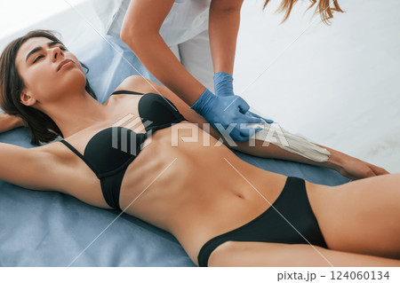 Putting cream on the hands. Woman is having sugaring procedure in the clinic by female doctor 124060134