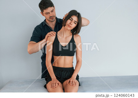 Moving the neck. Woman visiting physiologist that making massages and helping with traumas 124060143