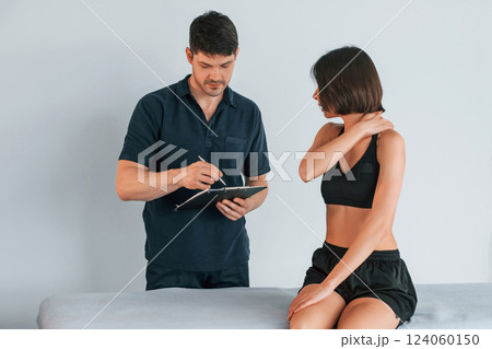 Sitting on the table. Woman visiting physiologist that making massages and helping with traumas Sitting on the table. Woman visiting physiologist that making massages and helping with traumas 124060150