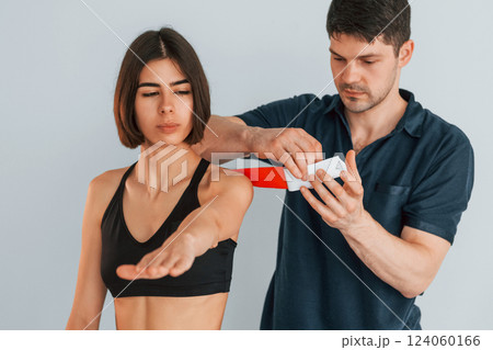 Focused worker. Woman visiting physiologist that putting kinesio tape on the skin Focused worker. Woman visiting physiologist that putting kinesio tape on the skin 124060166